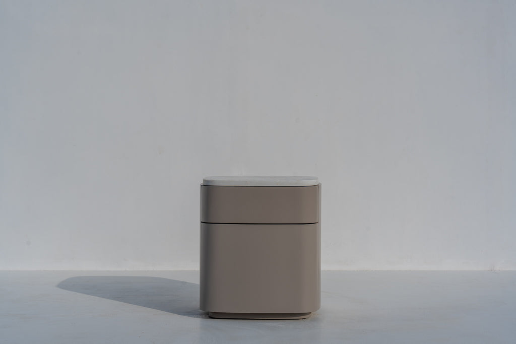 Arca curved bedside table with white stone top against a white wall, angled view