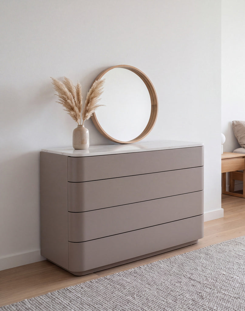 Arca rounded chest of drawers in taupe with stone top, styled with a round mirror in a bedroom