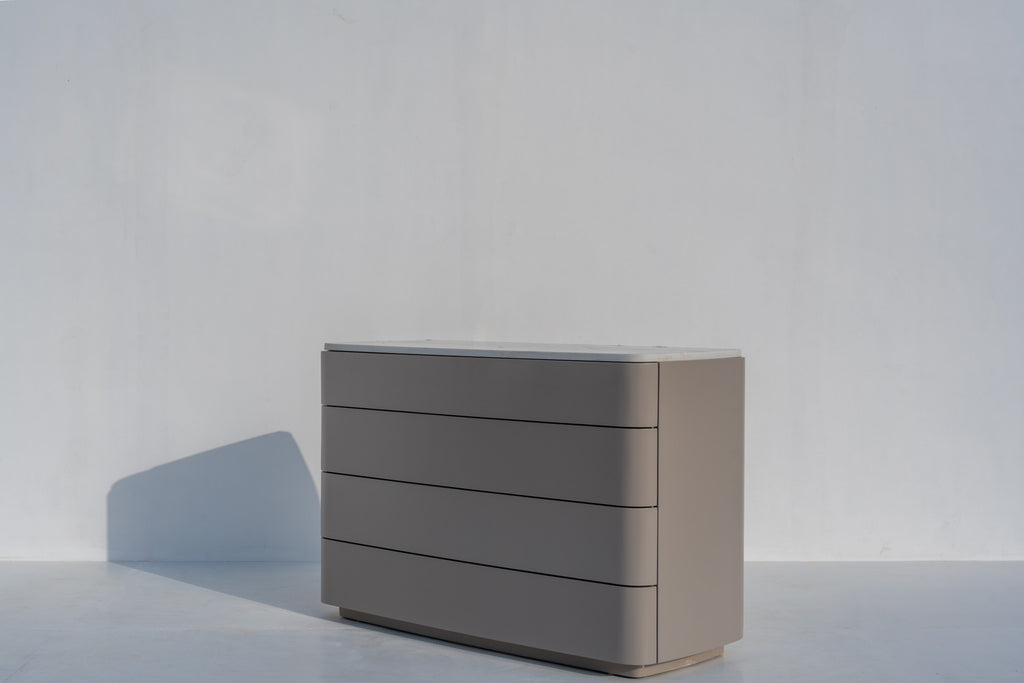 Arca rounded chest of drawers against a white wall, angled view
