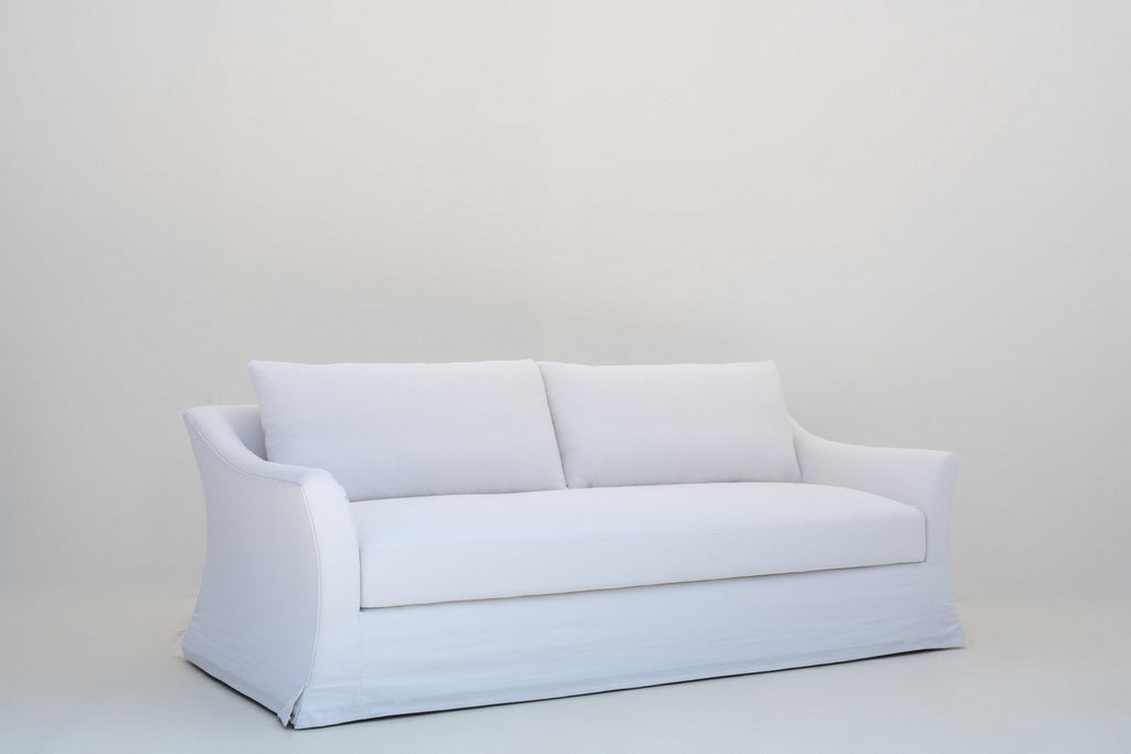 White Belgian linen sofa, three-quarter view with swoop arm and skirted base