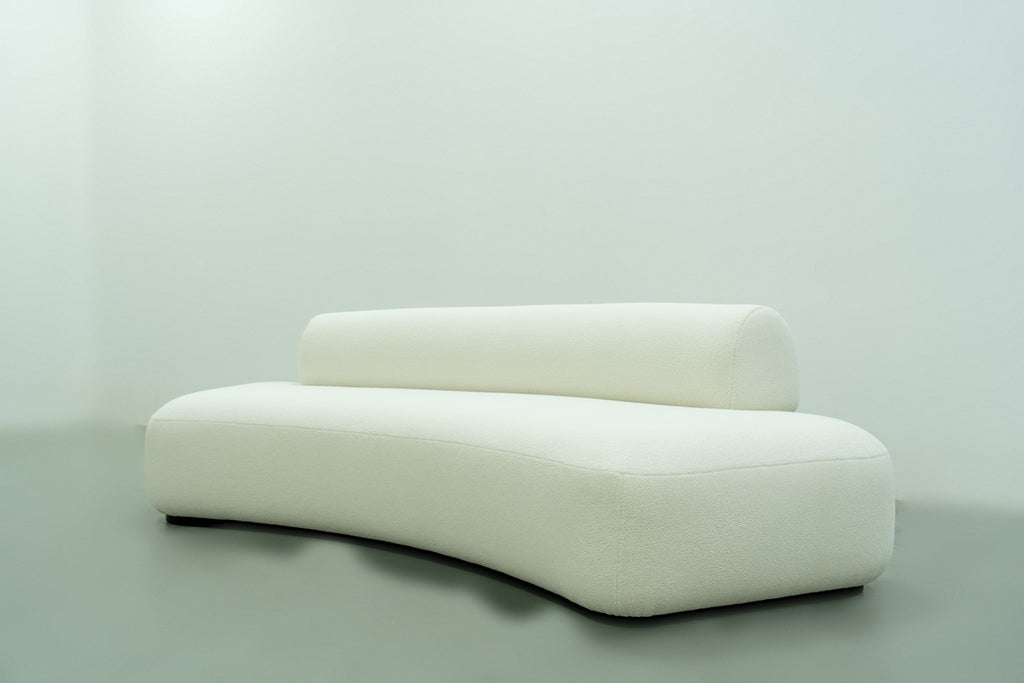 Dune curved sofa side angle showing the sweeping arc and recessed black plinth base