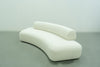 Curved bouclé sofa with a crescent-shaped seat and round bolster back, three-quarter view