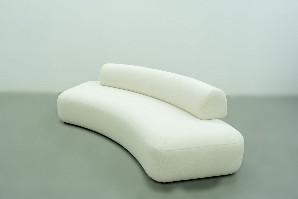 Curved bouclé sofa with a crescent-shaped seat and round bolster back, three-quarter view