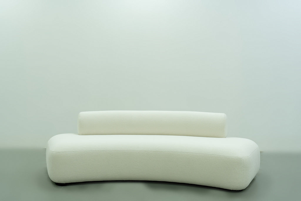 Modern curved sofa in ivory bouclé on a floating black plinth, front view