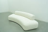 White bouclé sofa with a sweeping curved seat and offset bolster backrest
