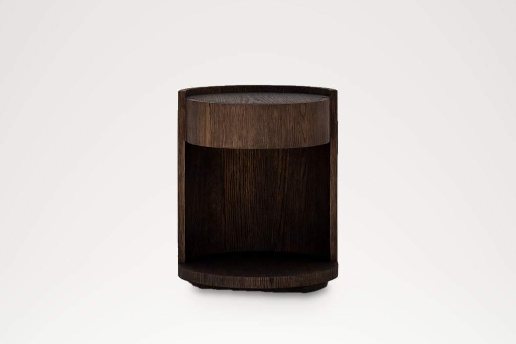 Round dark oak bedside table with drawer and open shelf, straight-on view