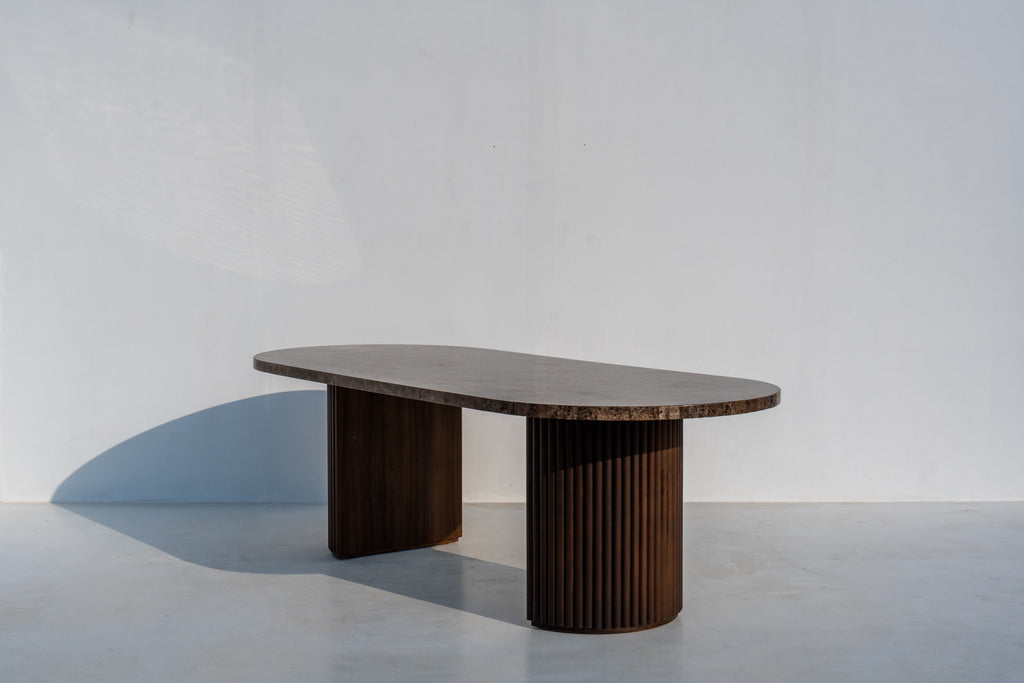 Livia racetrack dining table with dark marble top and ribbed walnut pedestals, side view