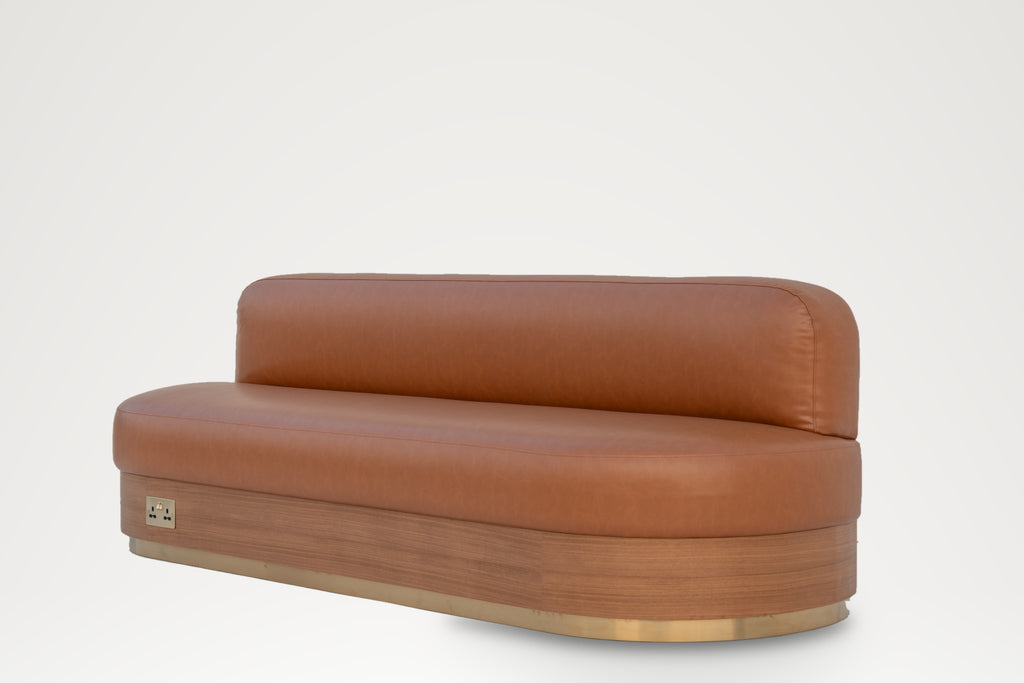 Marylebone Banquette three-quarter view, tan leather seat on a curved veneer and brass base