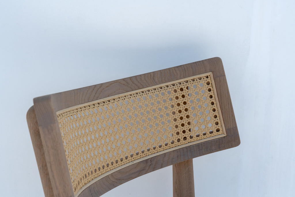 Close-up of the curved oak backrest with natural woven cane panel on the Ojai bar chair