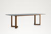 Pietra dining table, three-quarter view showing the open teak legs with V-shaped feet