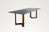 Pietra outdoor dining table, three-quarter view showing stone veining and teak legs