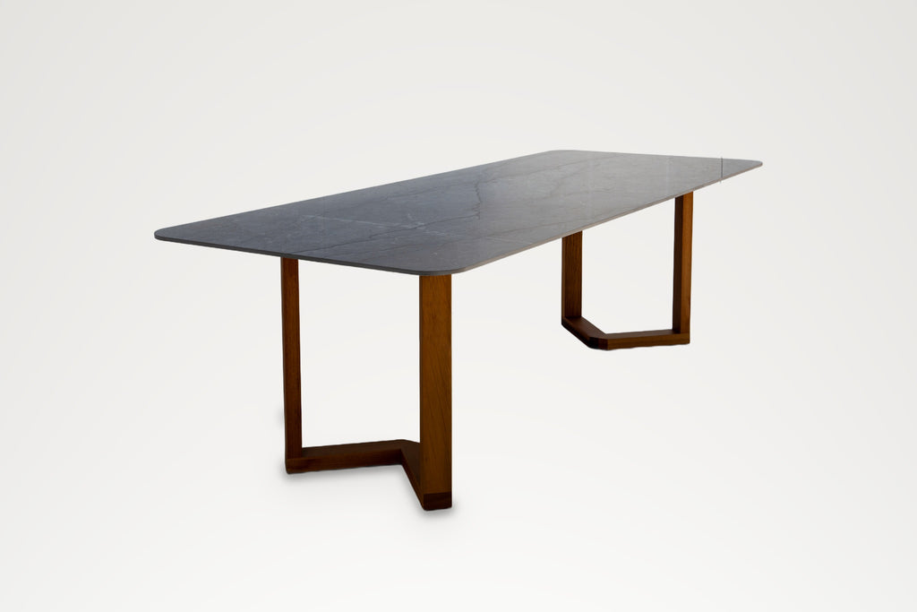 Pietra outdoor dining table, three-quarter view showing stone veining and teak legs