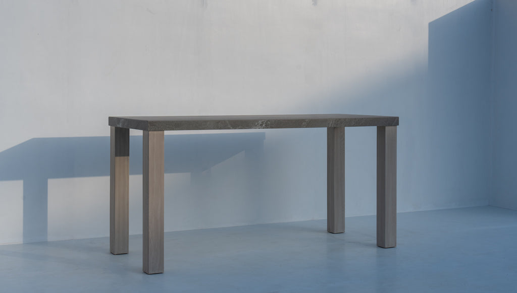 Pietra stone top bar table with teak legs at 110 cm bar height, three-quarter view