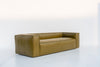 Olive green leather sofa with welted seams and boxy track arms, angled view