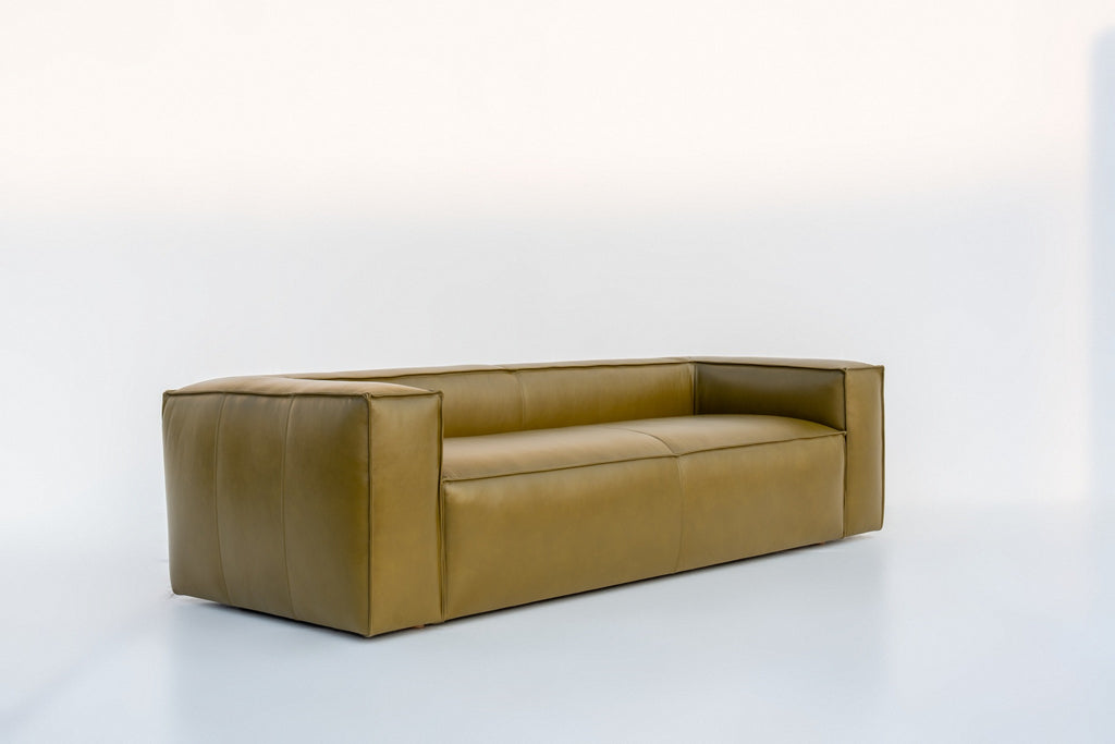 Olive green leather sofa with welted seams and boxy track arms, angled view